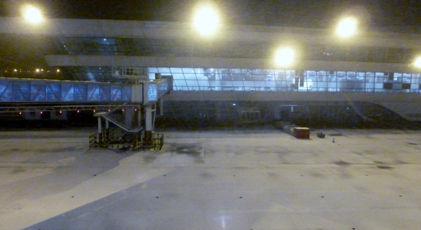 Snow is falling.  Jetway is in place on the left.