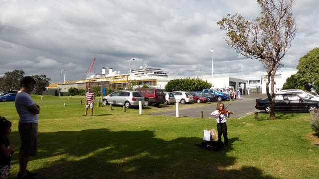 View of the ship from the park and a young child performing on his violin.