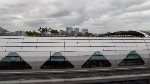 Looking at the Kai Tak Cruise Terminal with roof garden and city view behind.