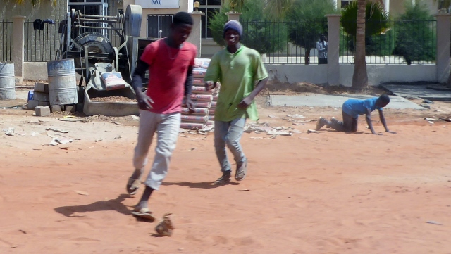 Schoolkids playing soccer without a soccer ball.